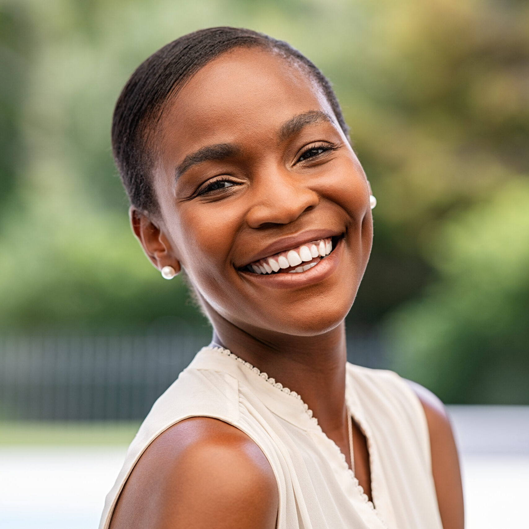 Portrait of smiling middle aged african woman looking at camera. Cheerful black mid adult woman smiling outdoor. Close up face of beautiful black lady laughing at park.